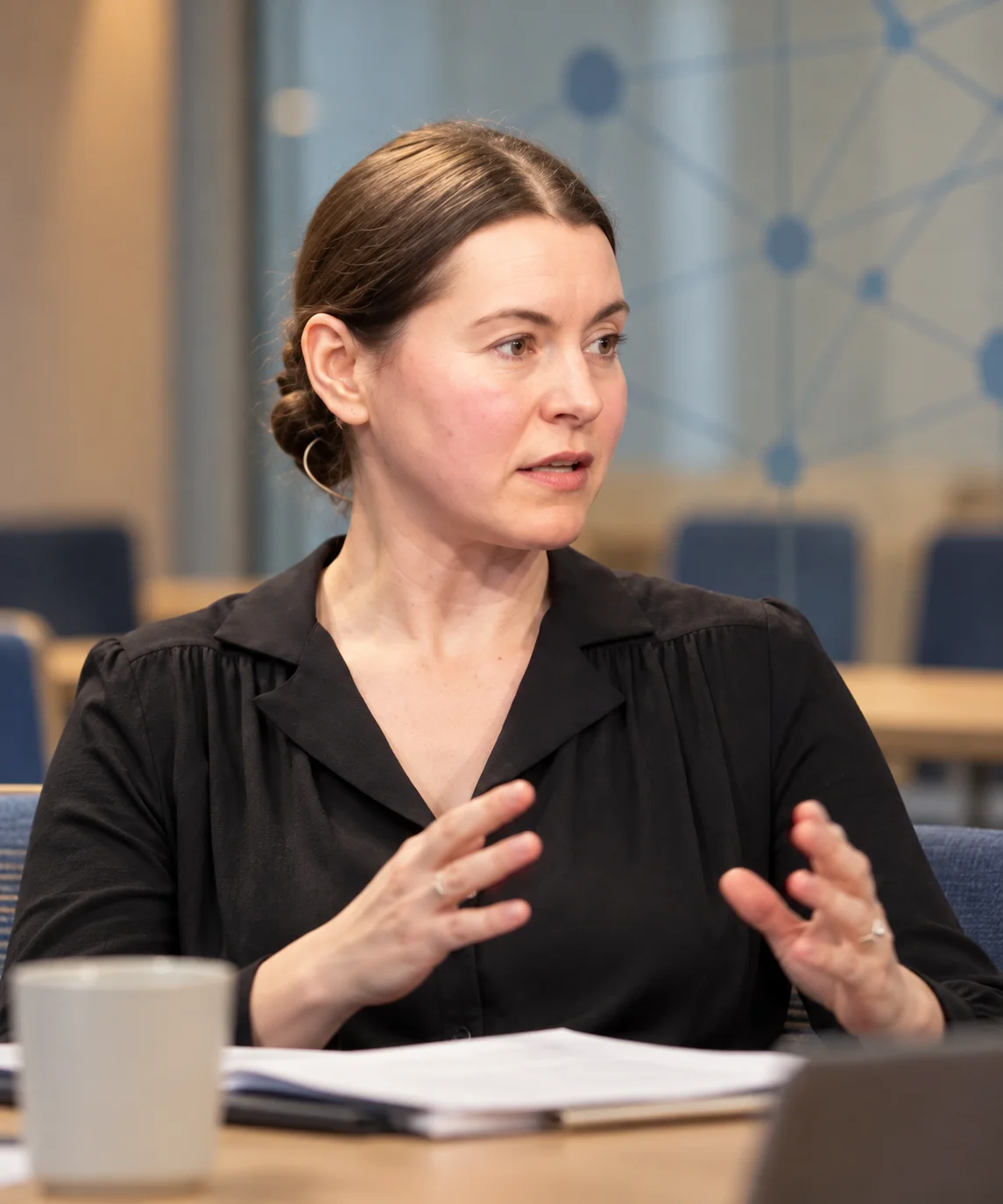 AI editorial portrait of Alena Muravska in an illustrative community meeting setting