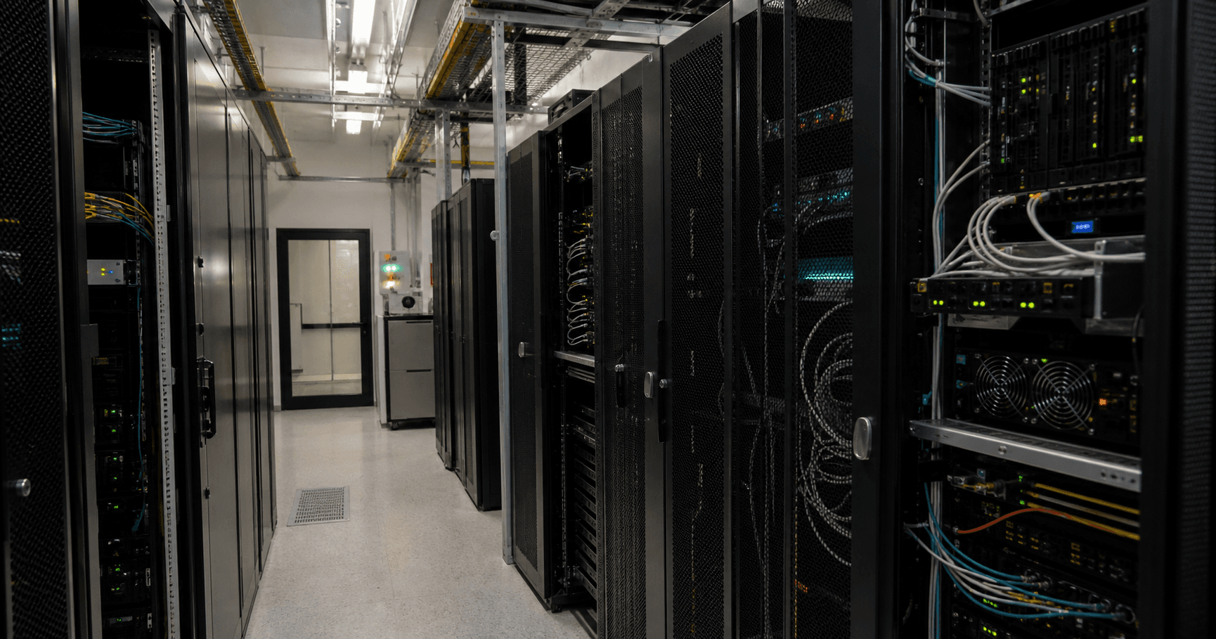 Inside a RZ OWL data centre in Bielefeld: a technician checks a backup storage unit in a quiet aisle of server racks.