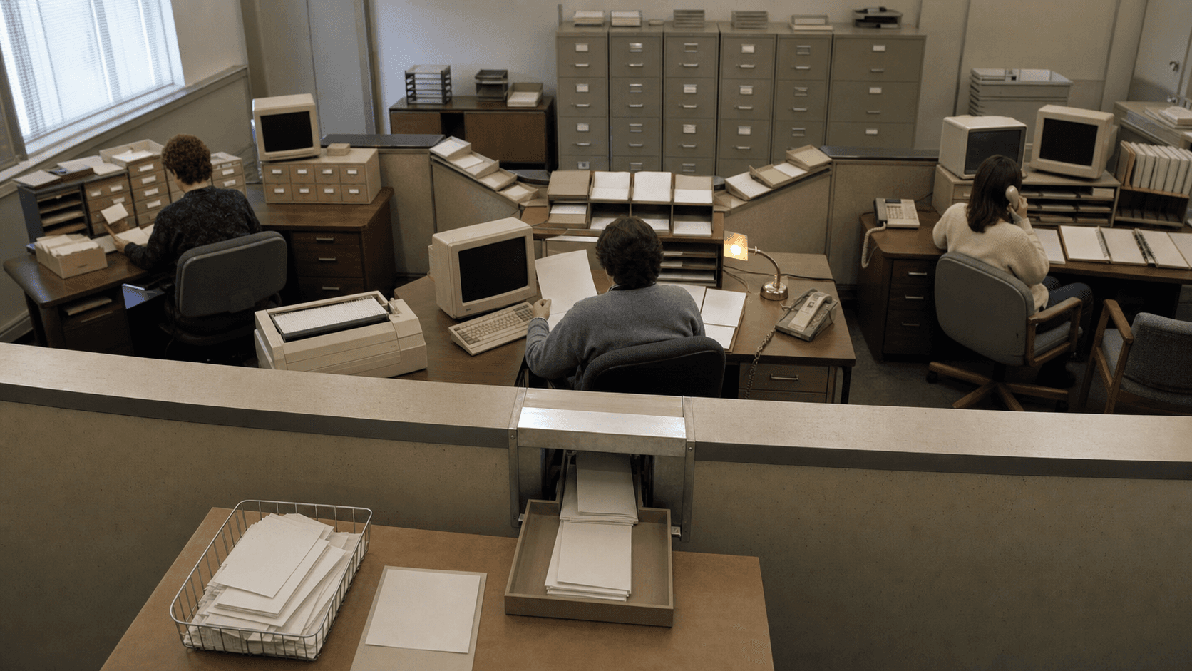Three early-1990s service stations share records, while blank registration requests enter through a single central intake hatch for processing.
