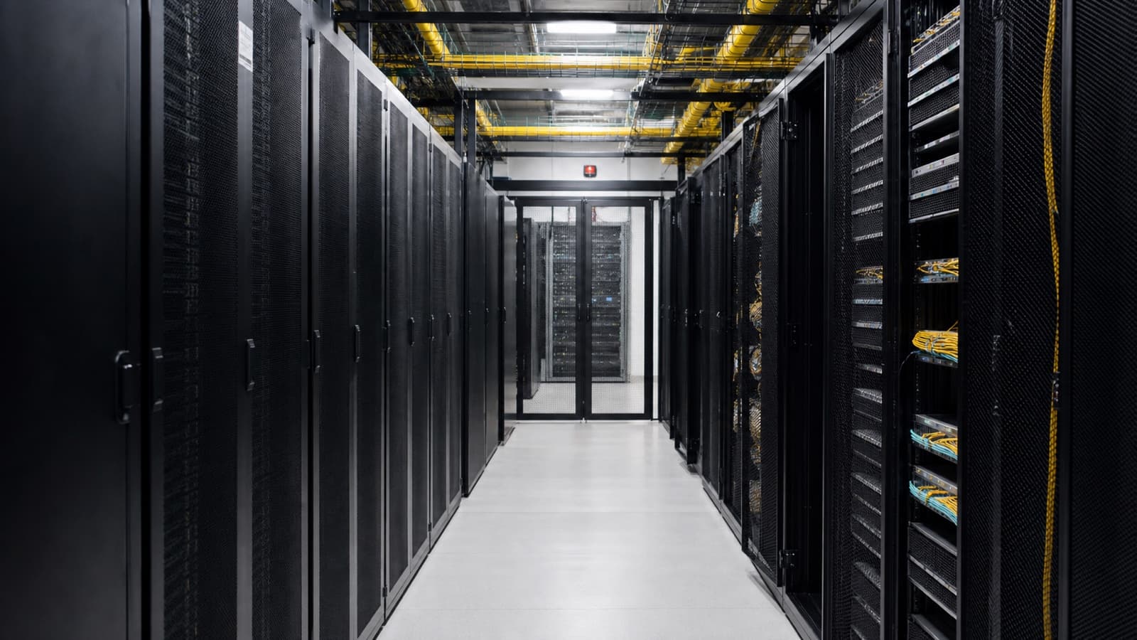 A clean aisle of unbranded server cabinets with overhead power and network cabling.