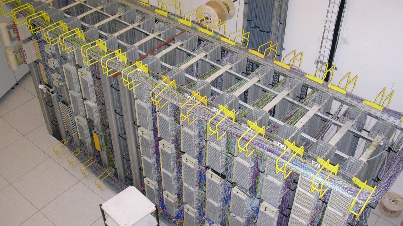 A telecommunications distribution frame routes dense multicolored cabling through metal frames.