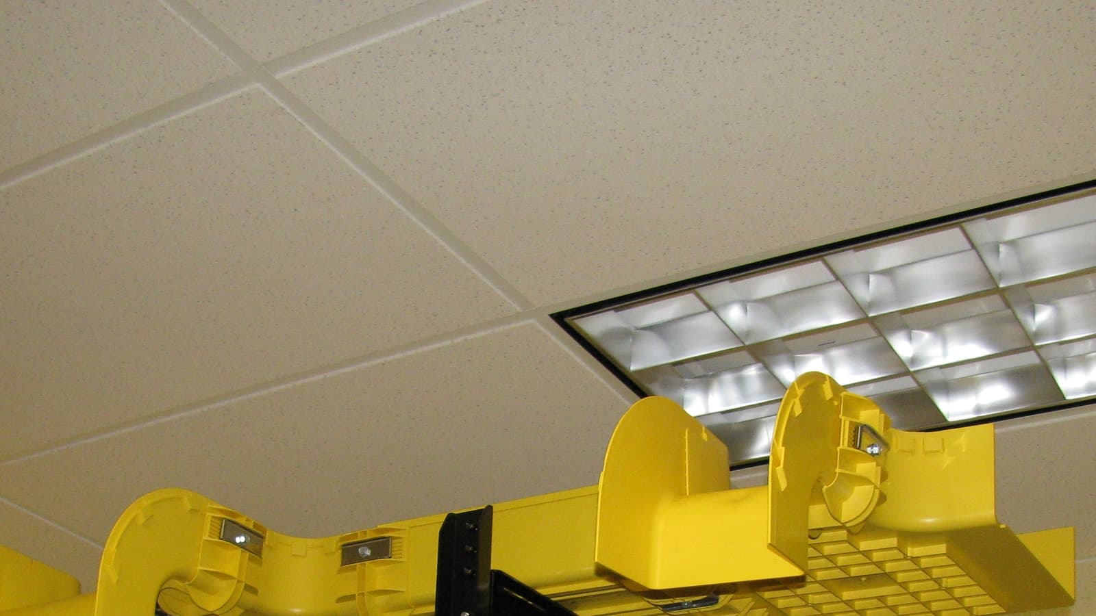 Overhead yellow fiber-optic cables organized in a network cable-management installation.